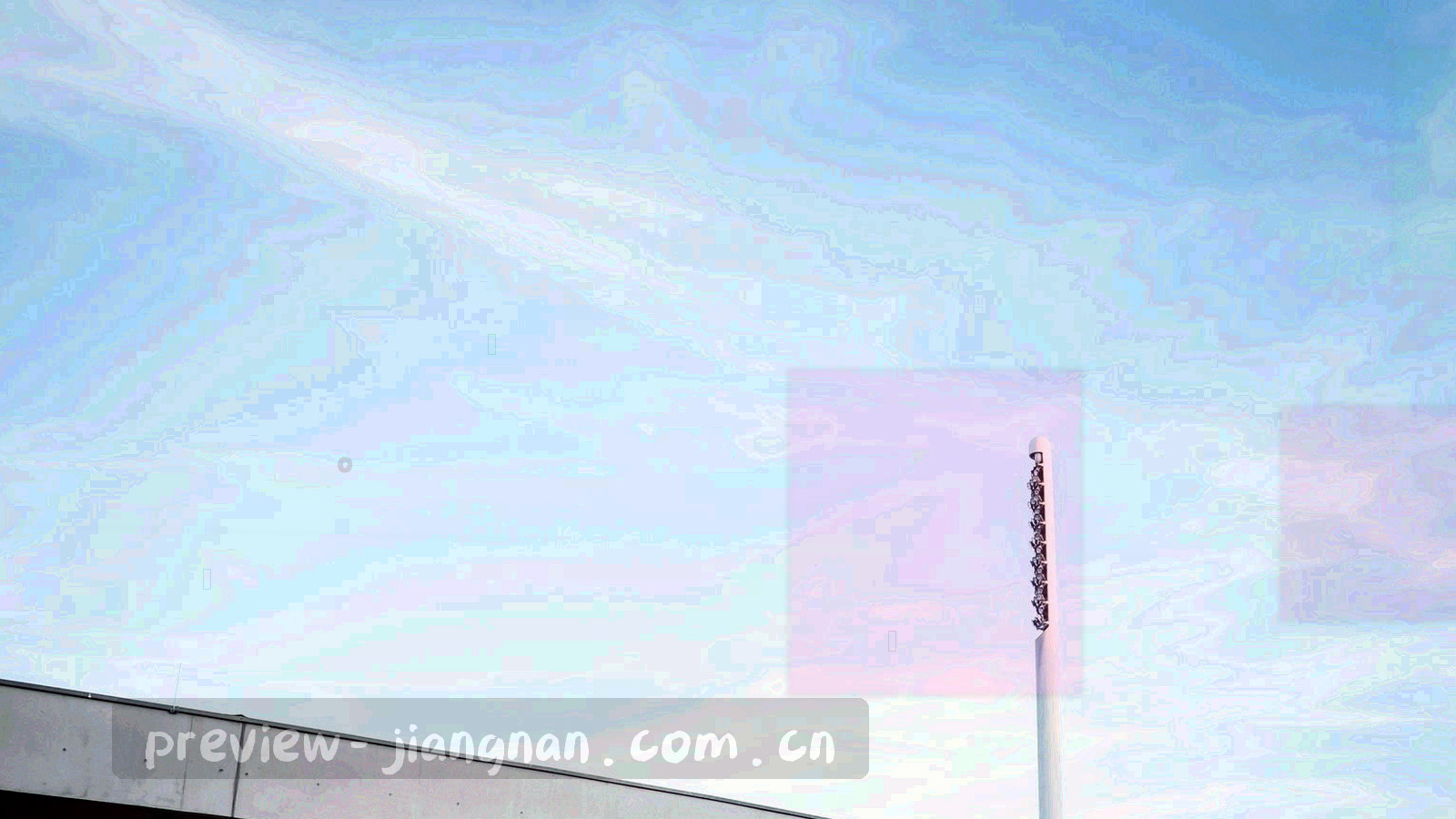 低角度广角下的高原球场看台，彩色布幡在风中飘动，远处是连绵的山脊